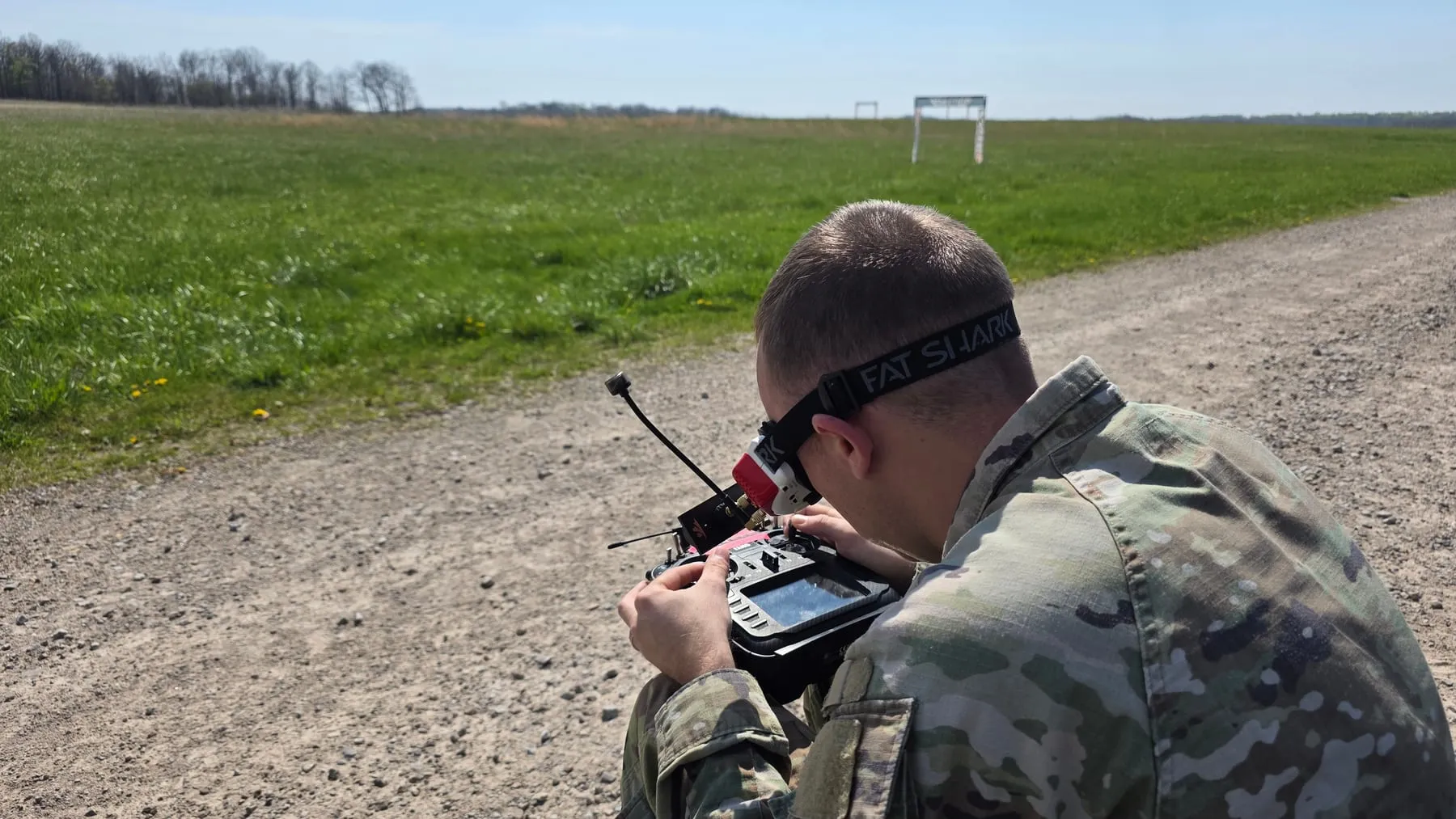 An operator flying an FPV aircraft with video goggles in an open field.